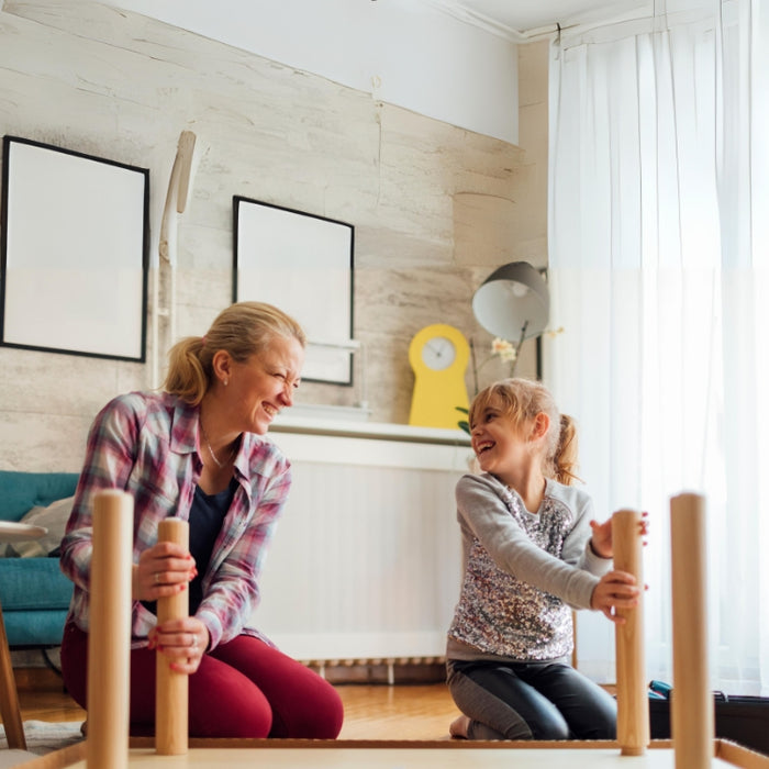Image of a mother and daughter laughing together as they work on a DIY furniture project at home, celebrating Mother's Day by creating memories.