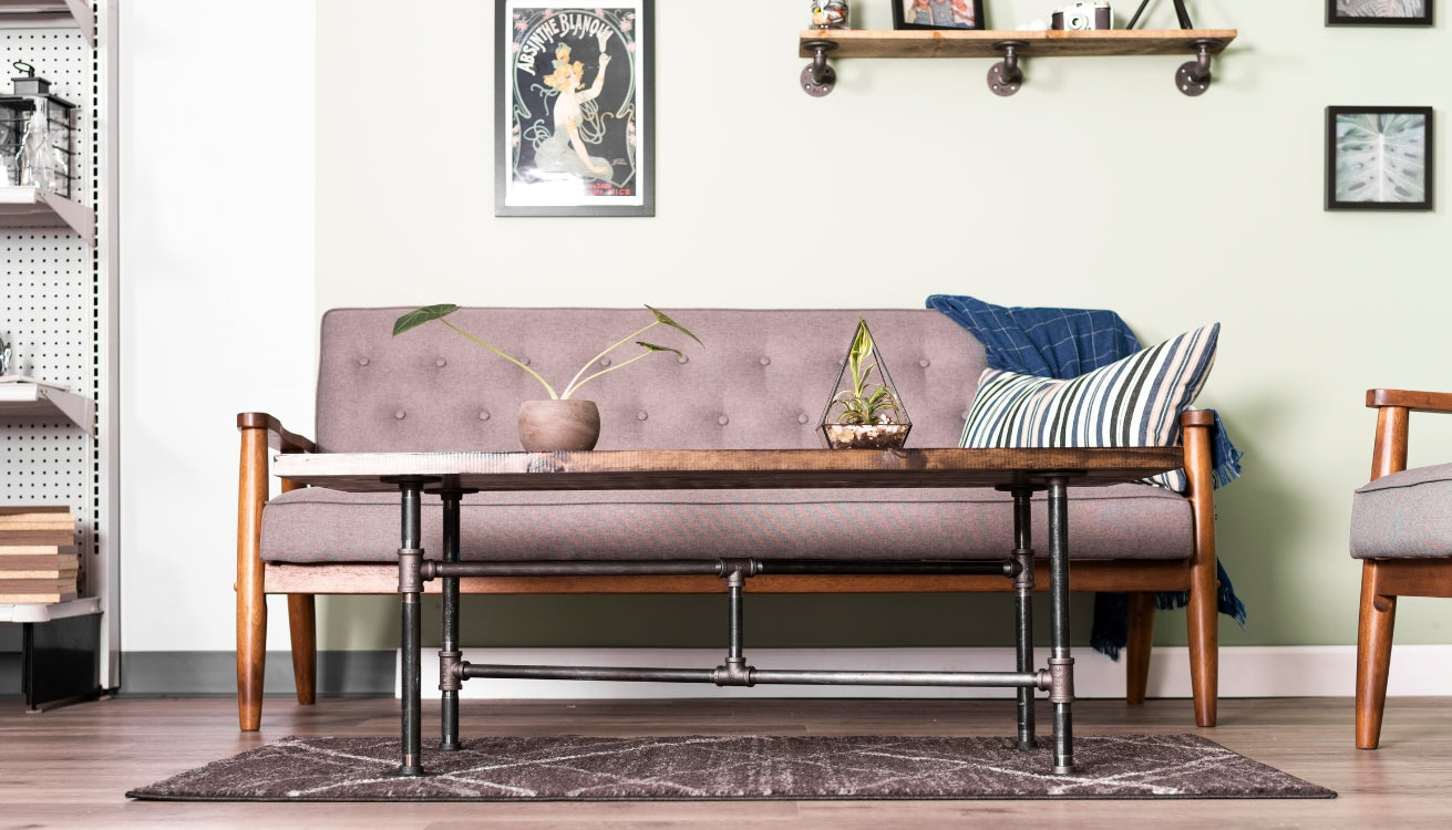 Stylish living room setup with a pipe cofee table, a couch, chair, and pipe shelving. 