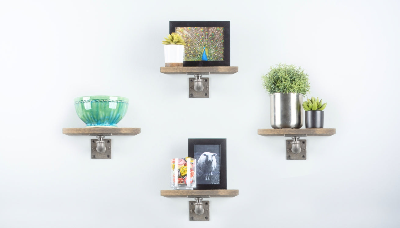 Four small industrial pipe shelves mounted on a white wall, showcasing a variety of decorative items, including plants, framed photos, and a ceramic bowl.