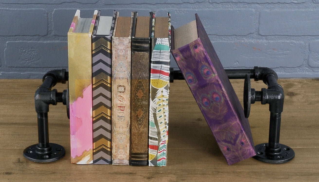 Stylish pipe bookends with a black finish holding colorful books upright, adding an industrial touch to the decor.