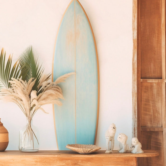 Coastal-themed console table decor with a surfboard, pampas grass, and ceramic figurines, ideal for a relaxed, beach-inspired home.