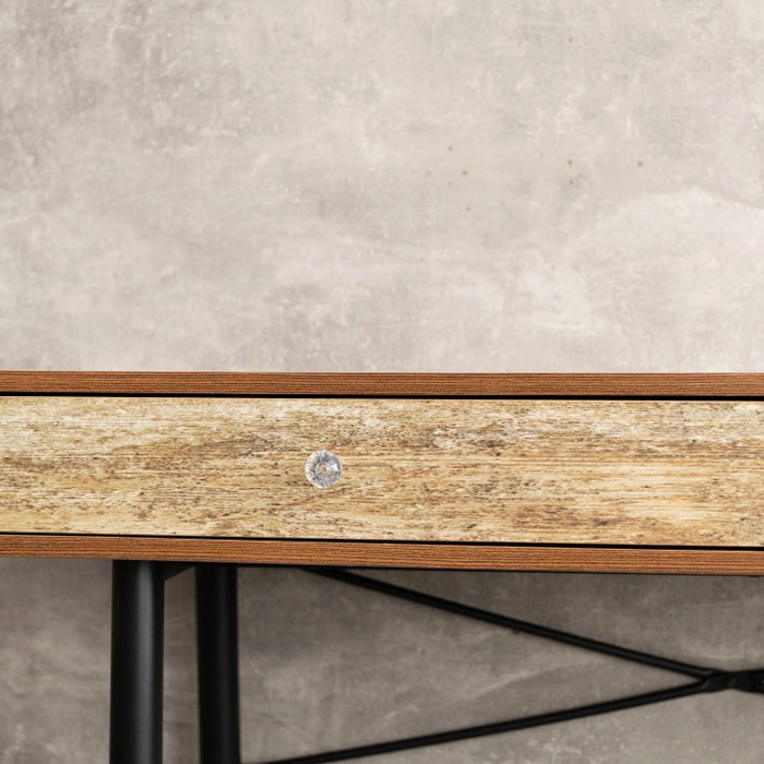 A close-up of a rustic wooden console table with mixed wood finishes, featuring sleek black legs and a minimalist design, set against a textured concrete wall.