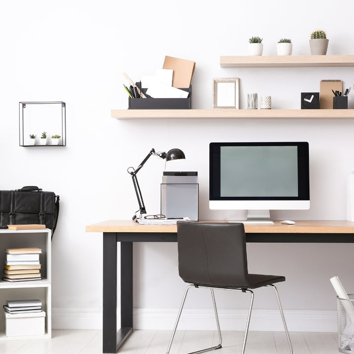 Image of a modern home office with a wood-top desk, black legs, floating shelves, and neatly arranged supplies for efficient organization.