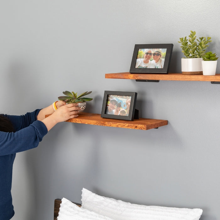 Image of a woman arranging potted plants and family photos on wooden PIPE DECOR® shelves, a thoughtful Mother's Day gift enhancing her home décor.