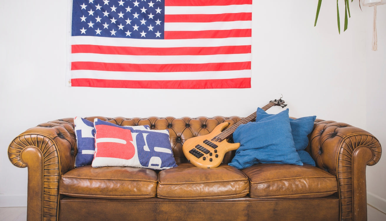 Vintage Americana living room with a classic leather sofa, American flag, and industrial pipe furniture accents for a timeless, patriotic vibe.