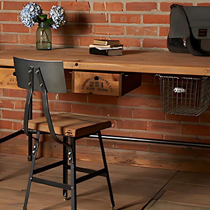 A modern industrial-style office desk featuring a natural wood top and sturdy black metal pipe legs, paired with a vintage metal chair and rustic decor.