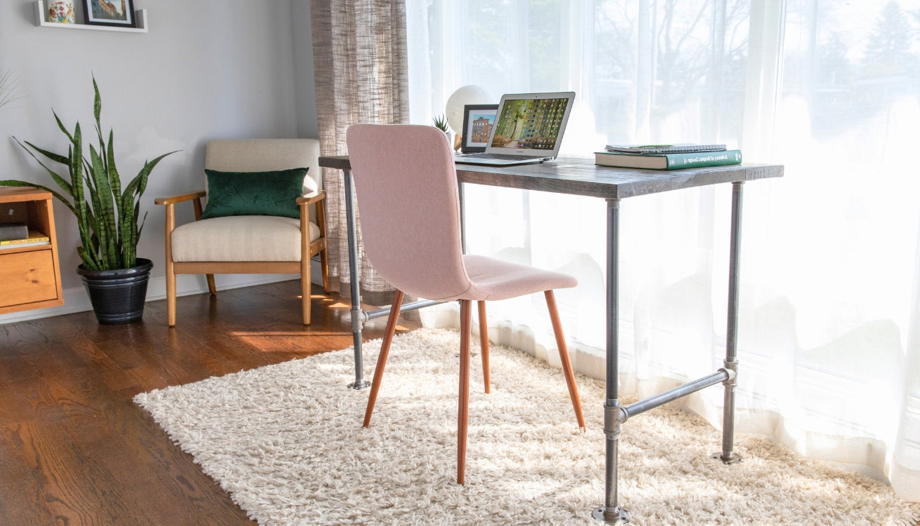 Bright and cozy home office featuring a minimalist industrial pipe desk, paired with a modern pink chair, perfect for productive work sessions.