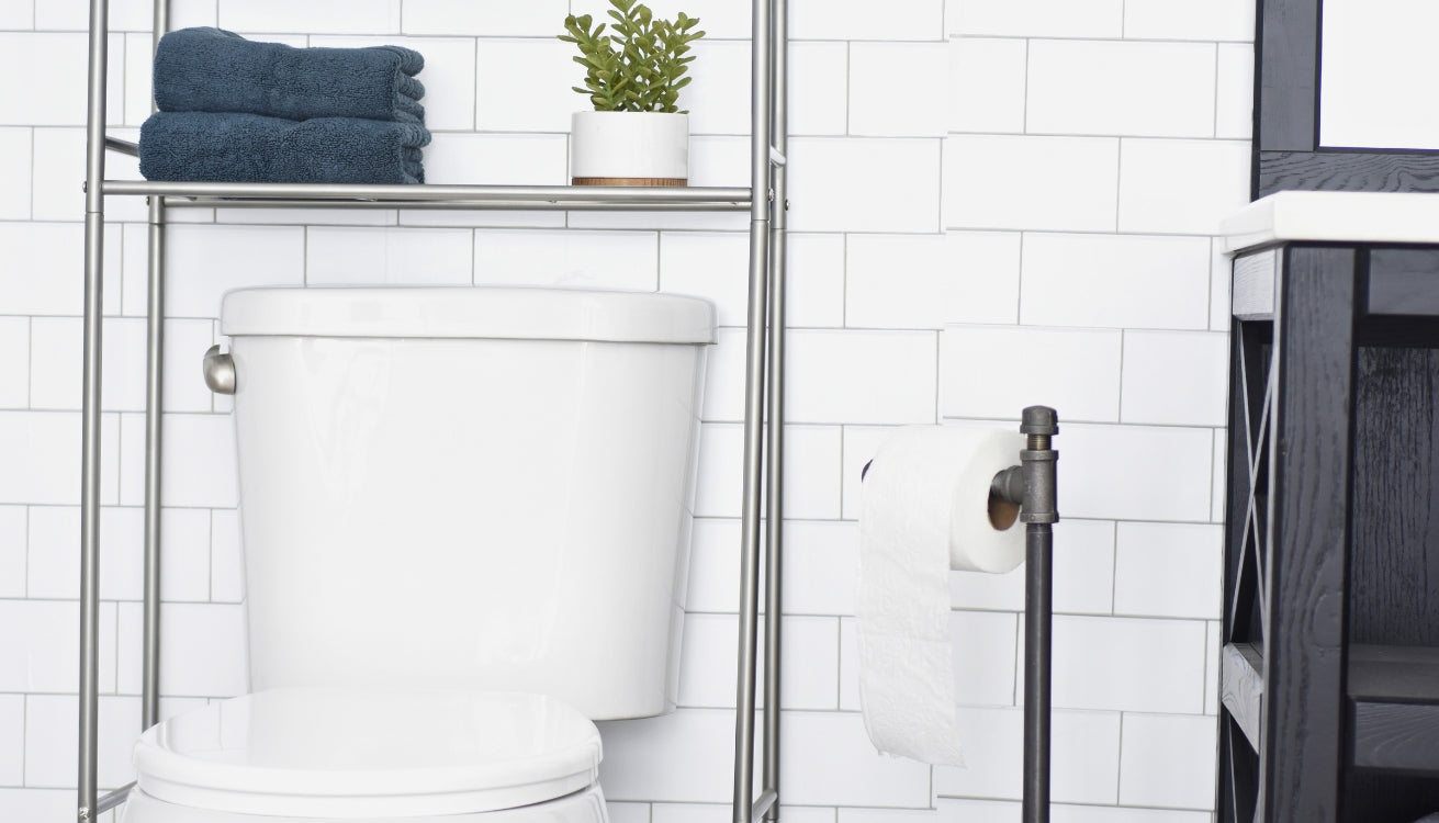 Freestanding industrial pipe toilet paper holder in a modern bathroom with white subway tiles and minimalist decor.