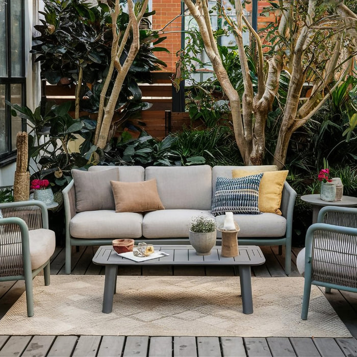 A cozy small patio setup with gray outdoor furniture, surrounded by lush green plants, creating a serene and inviting outdoor retreat.