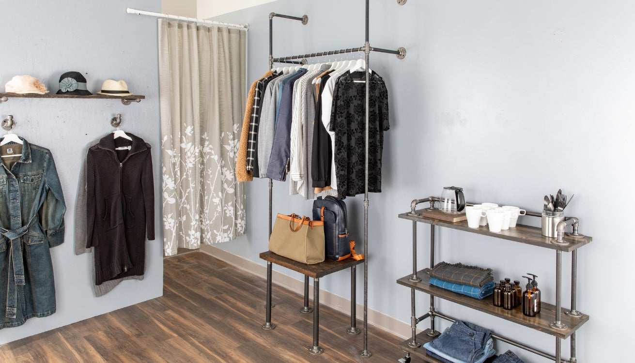 Industrial-style clothing rack and shelving unit in a minimalist room setup.