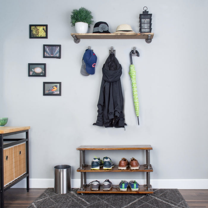 A small bedroom corner with PIPE DECOR® storage solutions including a wall-mounted pipe shelf, pipe hooks for hanging items, and a pipe shoe rack, showcasing stylish and functional storage hacks.