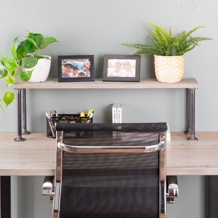 Minimalist pipe desk setup with a sleek metal chair, styled with plants, framed family photos, and office essentials for a clean and modern home office look.